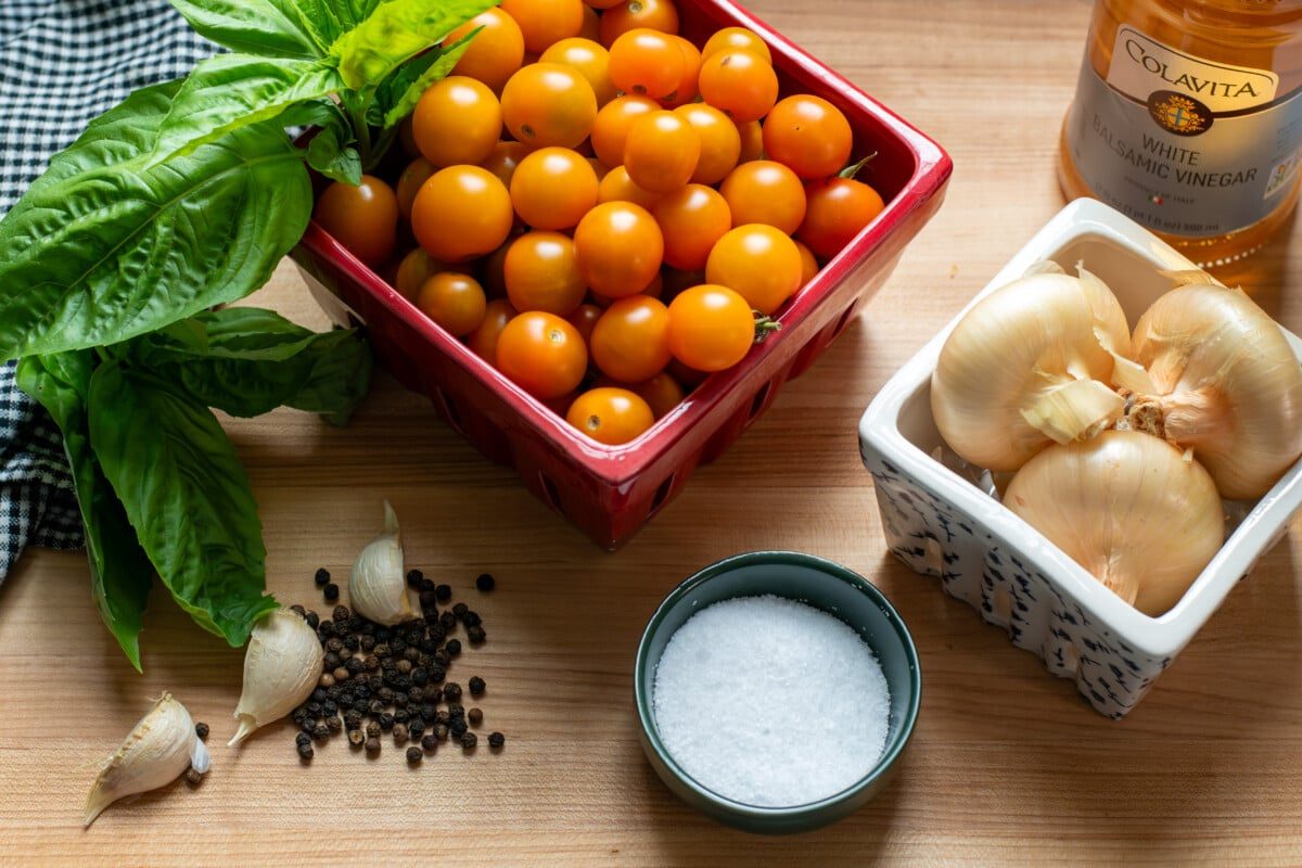 Cherry tomatoes, onions, a bottle of vinegar, salt, peppercorns, garlic cloves, basil leaves